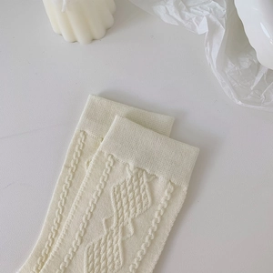 Detailed macro view of cream knit socks with diamond weave pattern and soft texture