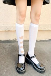 Détail de bas genoux blancs avec découpes circulaires et chaussures noires à plateforme