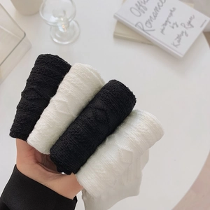 Detail of stacked black and white knit knee-high socks with diamond jacquard texture