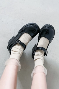 Close-up of black patent leather platform Mary Janes with stylish white crew socks