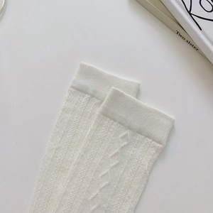 Close-up of white Lolita style knee-high socks with vertical stripes and hollow lace detail