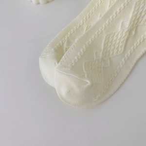 Detailed macro view of cream white knitted socks featuring hollow and cable knit patterns