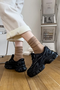 Close-up of black chunky sneakers with mesh panels and long cotton crew socks