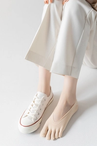 Close-up of beige low-cut five-finger invisible socks worn with canvas shoes