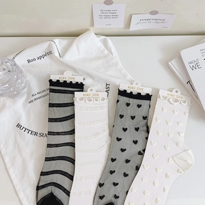 Flat lay of four pairs of sheer mesh socks with heart patterns and ruffle edges