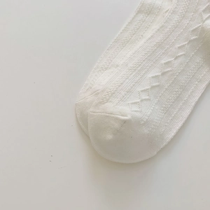Macro detail of white hollow knit socks featuring diamond patterns and mesh texture