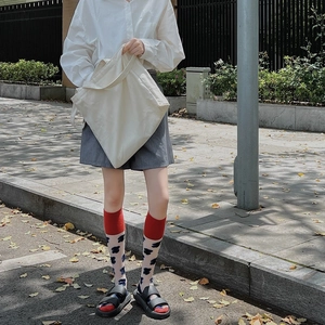 Detail of JK style mid-calf socks with red ribbed cuffs and floral patterns with sandals