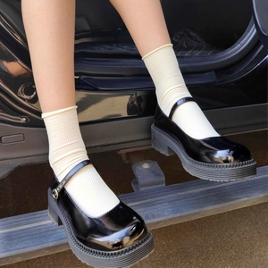 Women's black patent leather platform Mary Janes worn with off-white knit crew socks