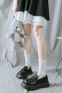 Détail de chaussettes blanches JK à motif cœur avec mocassins à plateforme et jupe