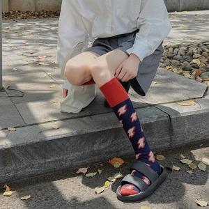 Navy blue knee-high socks with red cloud patterns shown on a park stone path
