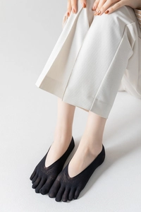 Close-up of black five-finger invisible socks with mesh texture on feet with white pants