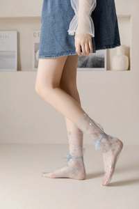 Detail of light blue mesh socks with silver snowflake patterns and delicate ankle bows