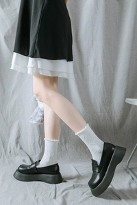 Détail de chaussettes blanches à motif cœur et bordure en dentelle avec mocassins noirs