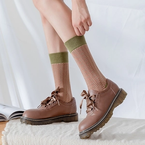 Detail of army green wavy socks paired with brown leather brogue shoes and silk bow laces