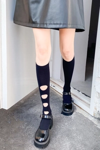 Détail de chaussettes hautes noires évidées avec design ajouré et chaussures noires