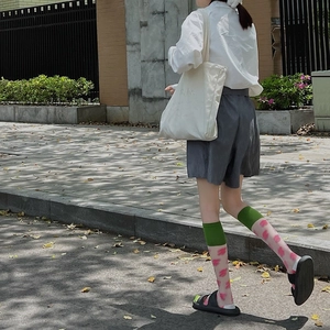 Green and pink patterned crew socks styled with black sandals and street wear