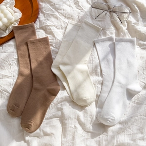 Detailed knit texture of mid-calf cotton socks in coffee, beige, and white colors