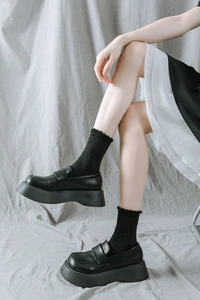 Détail de mocassins noirs à plateforme avec chaussettes en dentelle et boucle élégante