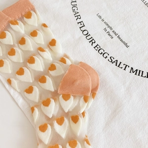 Detail of sheer mesh crew socks featuring orange heart patterns and soft cotton cuffs