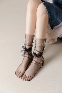 Detail of sheer black mesh socks with silver snowflake prints and silk bow accent