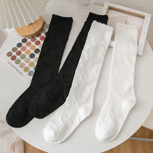 Détails à plat de chaussettes montantes blanches et noires avec motifs cœurs et papillons