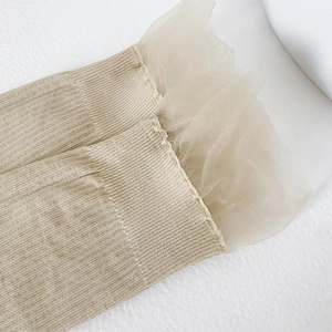 Detail of beige ribbed socks featuring delicate double-layered mesh lace trim and knit texture