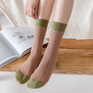 Retro houndstooth crew socks in beige and brown with green accents on a wooden bench