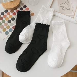 Détail de chaussettes hautes noires et blanches avec dentelle cœur et revers volantés
