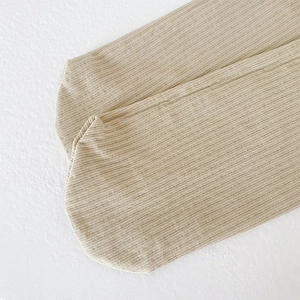 Close-up of beige ribbed knit cotton blend socks with a soft texture and vertical stripes