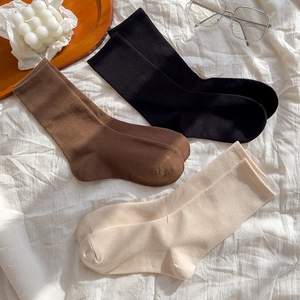 Flat lay of cotton mid-calf socks in black, brown and beige with ribbed cuffs