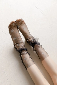 Detail of sheer black tulle socks featuring silver snowflakes and a chiffon bow embellishment