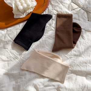 Flat lay of cotton crew socks in black, brown, and off-white on a fabric background