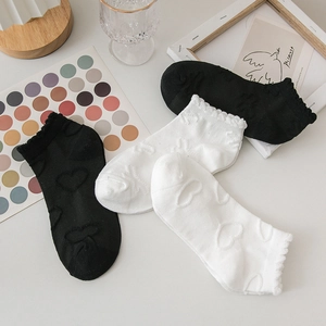 Détail de chaussettes hautes JK noires et blanches avec motifs cœurs 3D et bords à volants