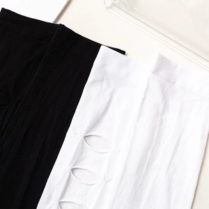 Détail de chaussettes hautes Lolita ajourées en tricot noir et blanc avec découpes