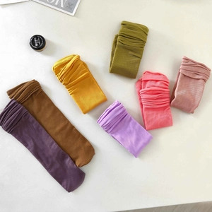 Flat lay of colorful ribbed velvet high socks in purple, yellow, pink, and green
