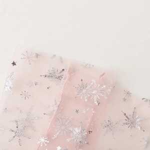 Detail of pink tulle fabric featuring shimmering silver snowflake and star patterns