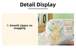 Detail of smooth white zipper and floral quilted fabric on this blue makeup bag