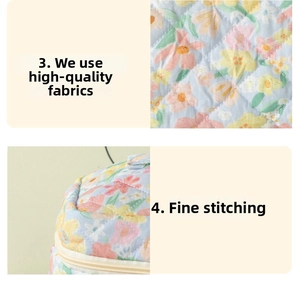 Detailed close-up of blue floral quilted fabric with pink flowers and stitching details