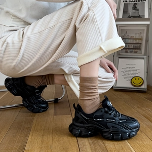Women's black chunky sneakers with platform soles in a stylish lifestyle setting