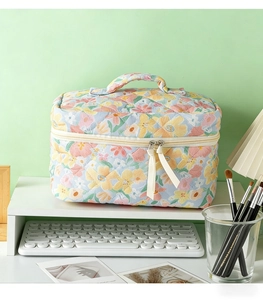 Detail of quilted floral makeup bag with light blue fabric and decorative white ribbon