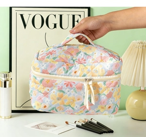 Detail view of floral quilted toiletry bag featuring a sturdy top handle and metal zippers