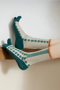 Detail of sheer two-toe socks with green polka dots, stripes and orange ribbed cuffs