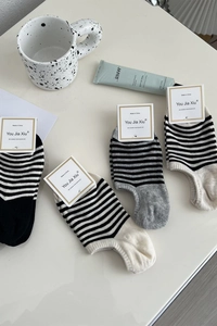 Gros plan sur quatre paires de chaussettes basses rayées aux motifs classiques noir et blanc