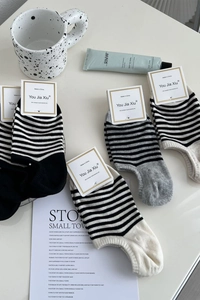 Vue à plat de chaussettes basses rayées en noir, blanc et gris avec emballage de marque