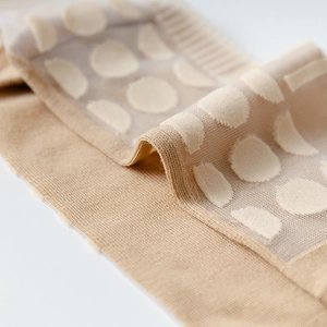 Detail of sheer polka dot mesh and ribbed cuff on beige two-toe Tabi socks for women