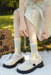 Detail of breathable white mesh crew socks with yellow tulip patterns and Mary Janes