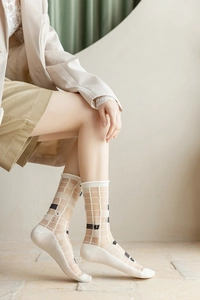Détail de chaussettes en résille transparente avec motif quadrillé et fleurs noires