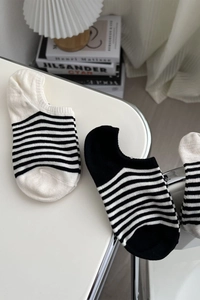 Détail macro de chaussettes bateau en coton à rayures noires et blanches sur bureau blanc