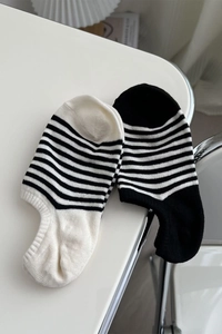 Détail de chaussettes invisibles à rayures noires et blanches sur une table blanche