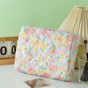 Quilted floral makeup bag in light blue with pink flowers on a white surface